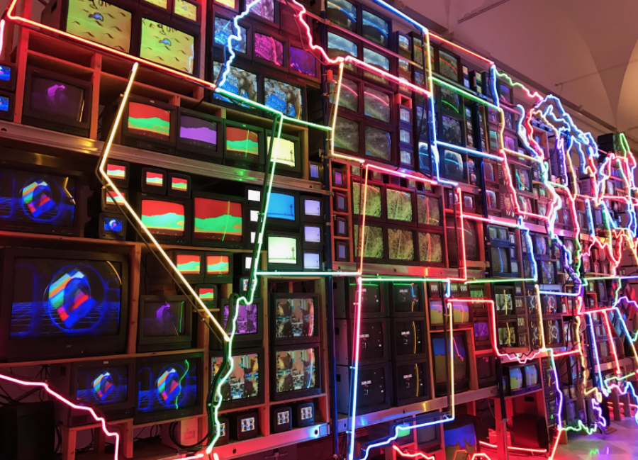 Various-sized televisions, outlined by neon lighting, create the configuration of the United States.