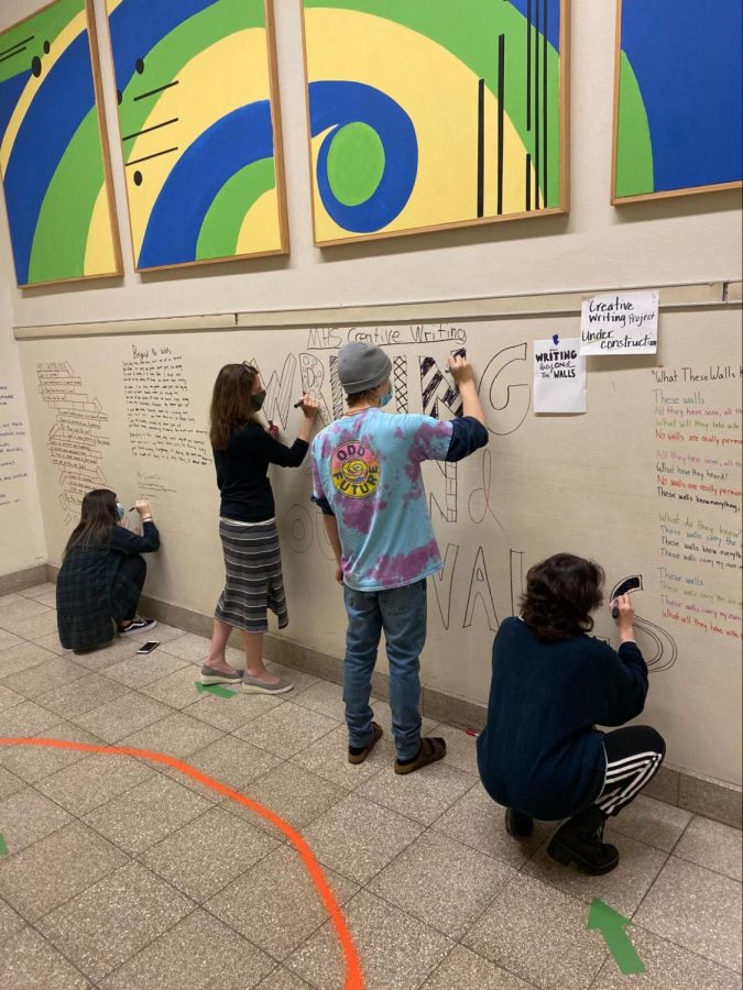Ohly and her creative writing students working together to create the “BeyONd our Walls” exhibit in the four corners staircase of MHS. Student writers combine poetry and design to display their works relating to the theme of “walls.”