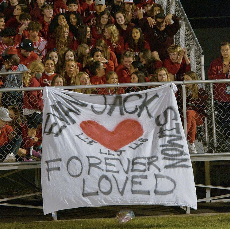 Students dressed in red at the boys varsity soccer game on Oct. 5 with a banner dedicated to Jack Miller, Evan Kratochwill, and Simon Bilessi.