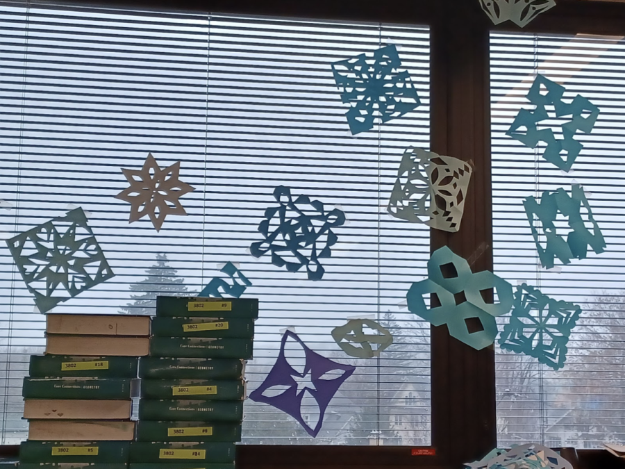 Photo of CPM Geometry books on a shelf in Ms. Hommowuns room. The windowsill is decorated with snowflakes in celebration of the upcoming season and break. 