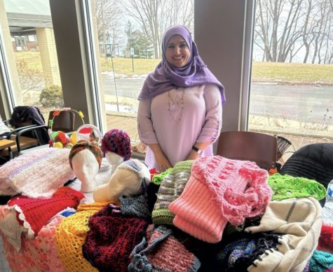 Huda, Co-founder of Knitting For Peace, stationed next to all of her colorful knits.