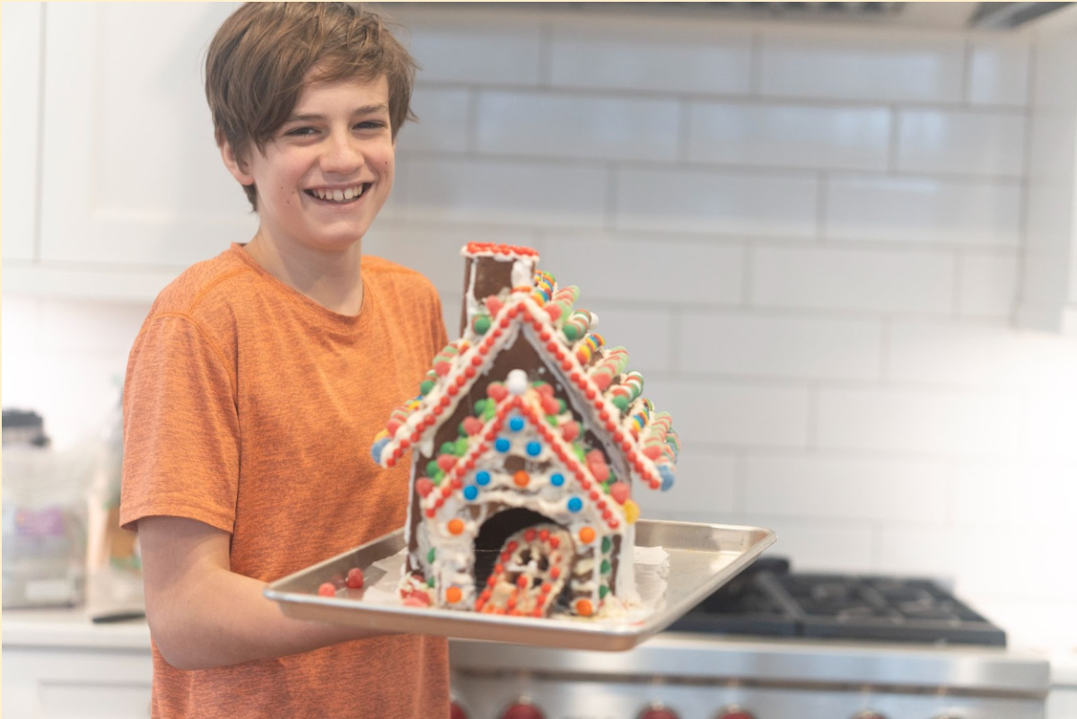 Simeon+Blust%2C+12%2C+poses+with+his+completed+gingerbread+house.+A+kitchen+enthusiast%2C+Simeon+loves+to+create+and+experiment+with+his+own+recipes.