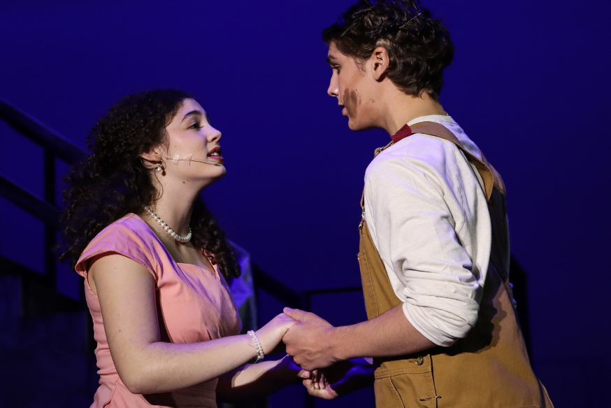 MHS Theatre students Ava Greenberg (10) and Owen Sehgal (11) stand together on stage as they perform the leading roles of Hope Cladwell and Bobby Strong in Urinetown.