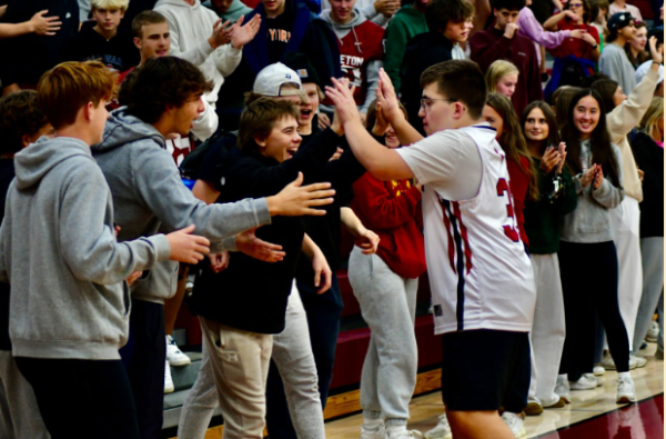 Jack Rothering (12) high fiving the student section at a soccer game. Showing Middleton high school's students supporting the players.
