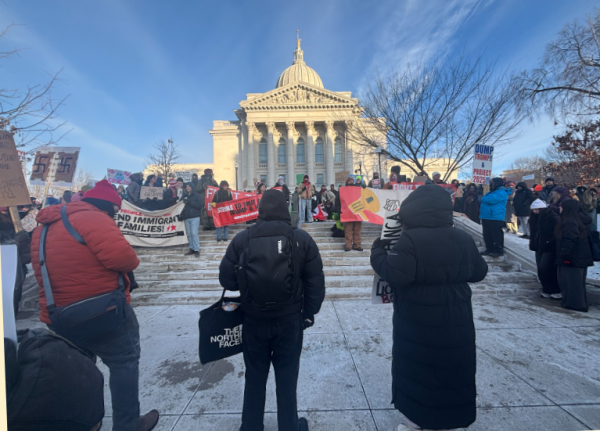 Individuals associated with the rally's organizers speak on topics related to ICE and the protest itself in front of the capital. One speaker chose to talk about abuse of undocumented immigrants who work at dairy farms in Wisconsin whose employers try to save money by not training them to operate dangerous equipment at the employees' own peril.