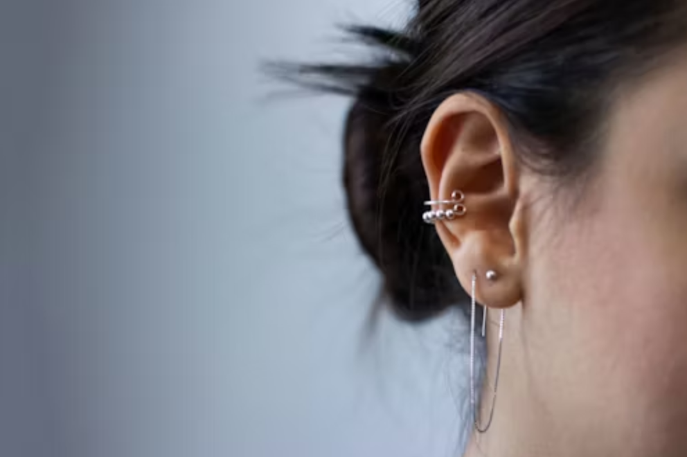 A photo of a girl with double earlobe and conch piercings.